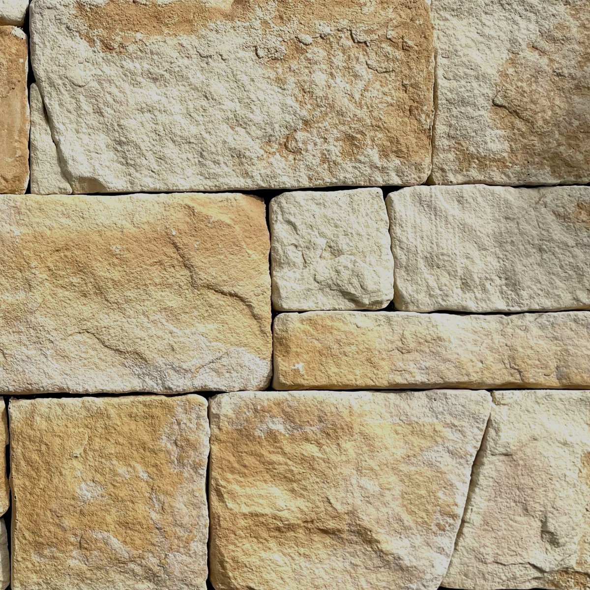 Close-up of tan and cream colored stone blocks fitted together in a stacked masonry wall pattern